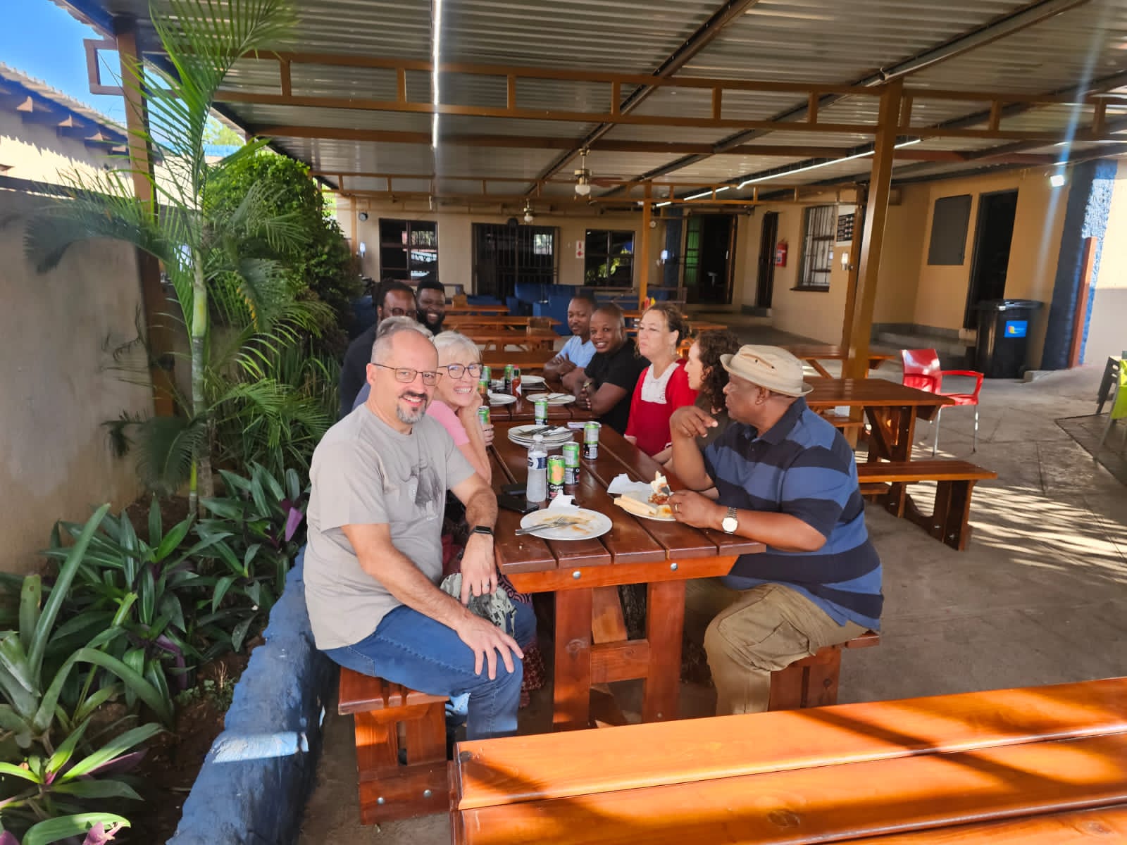 Delegates enjoying lunch on long wooden tables in the lodge's covered courtyard